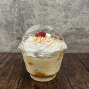 Tres leches dessert in clear cup with whipped cream and cherry topping